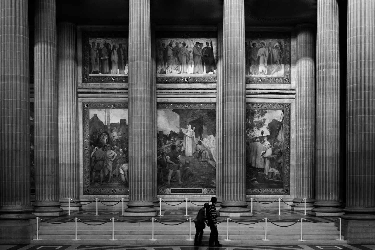 A couple are dwarfed by the wall length paintings and murals that line the interior.