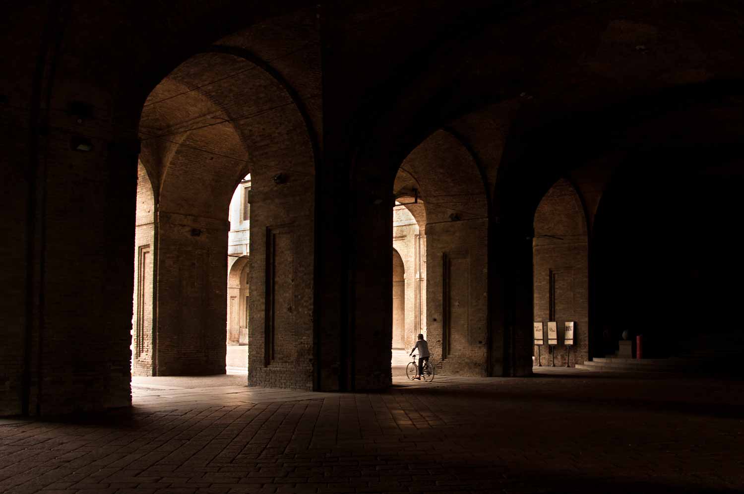 A cyclist takes a moment outside the entrance to the National Gallery of Parma.