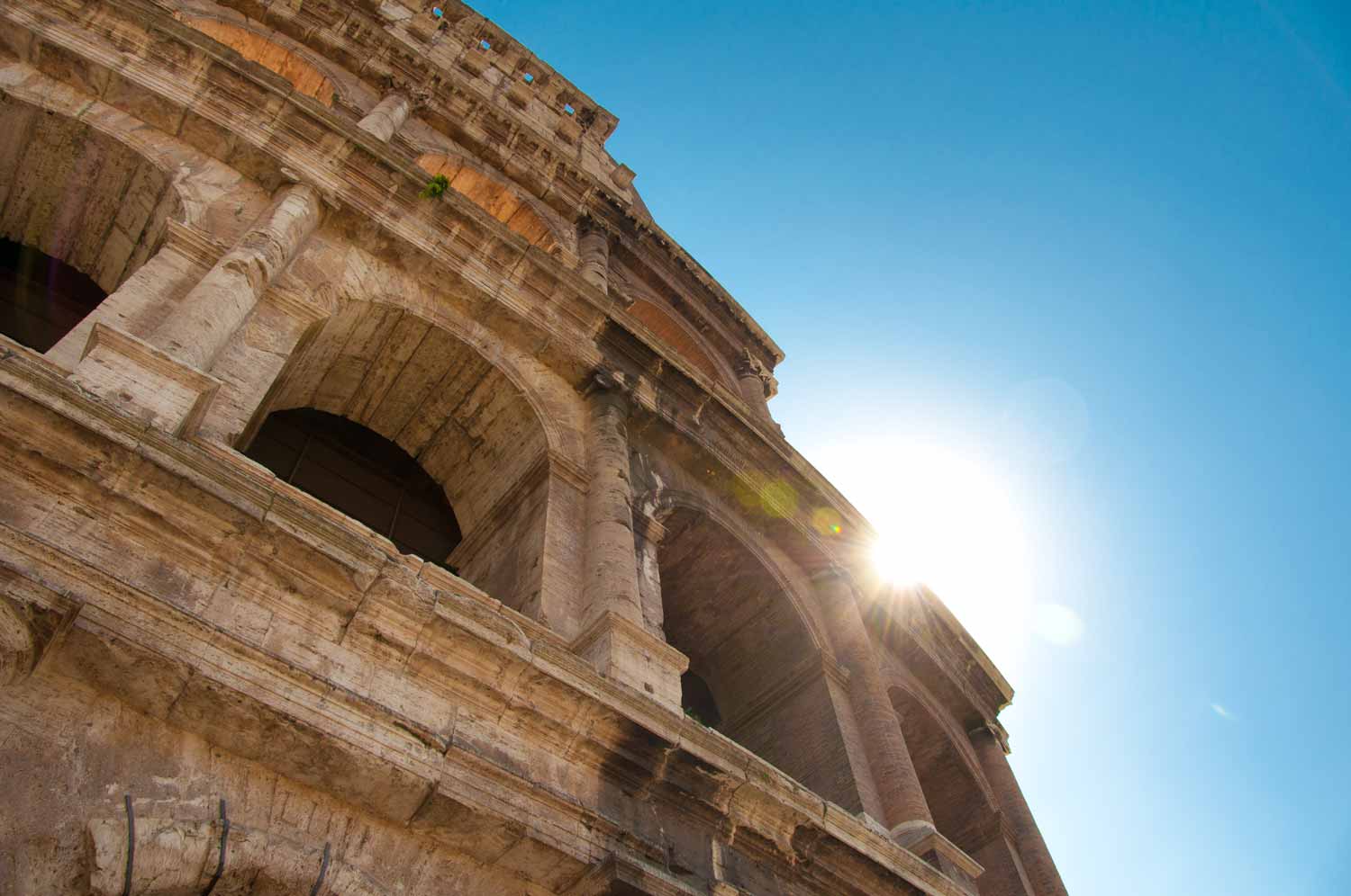 The early morning sun peaks over the Colloseum.
